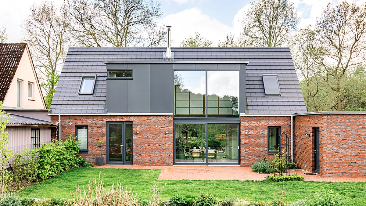 Modernisierung und Umbau eines Einfamilienhauses mit großer Glasfront und HPL-Platten Verkleidung, Glattziegeln auf dem Dach