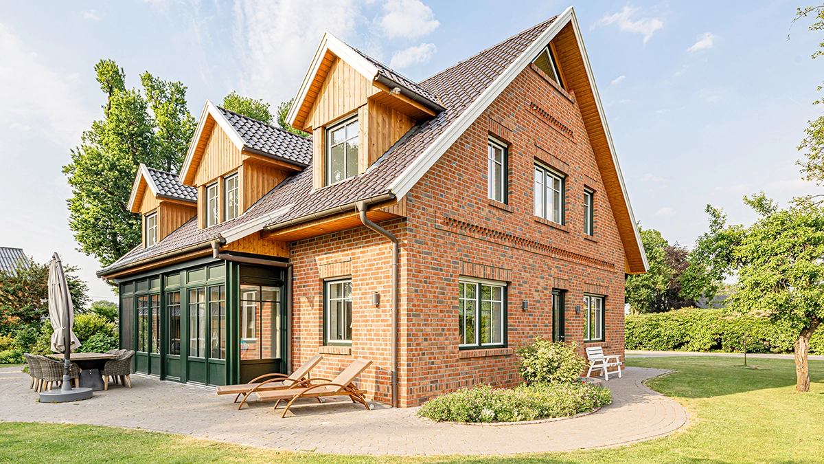 Sanierung Umbau Fachwerk Bauernhaus Landhaus mit Holzgauben und grünem Wintergarten